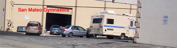 back corner of San Mateo Gymnastics building and building behind it with "NO GYMNASTICS PARKING" sign